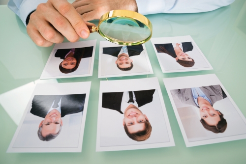 Close-up Of A Person Hand With Candidate Photograph And Magnifying Glass